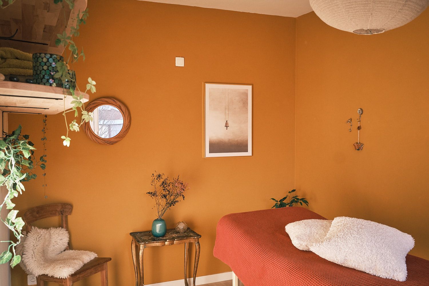 A view into the Cocon Jaune massage room. On the lef, a rack with plants and a chair in the corner. On the right, the massage table.