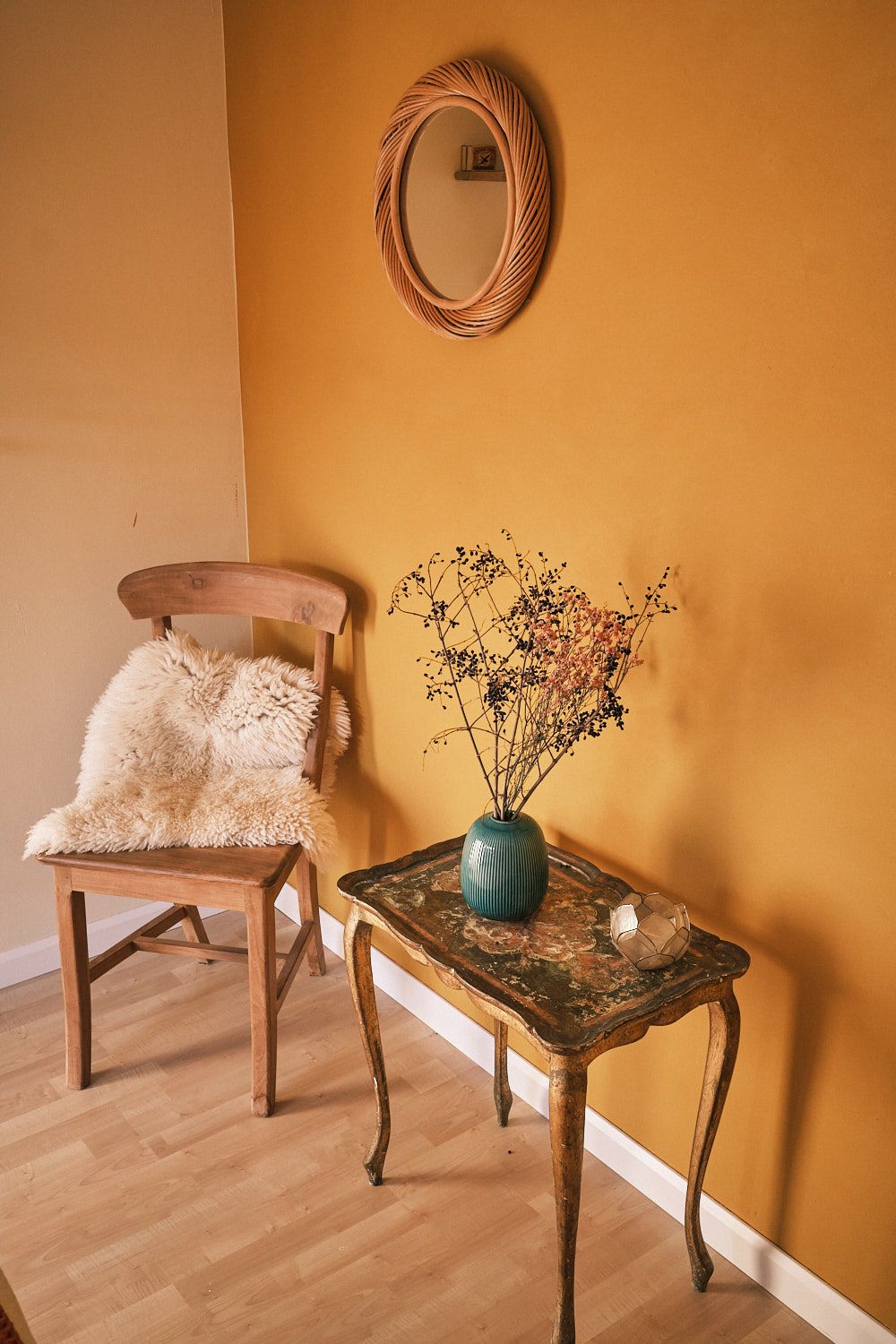 In the corner of the room stands a wooden chair with a sheepskin rug over it, next to it a table with tea.